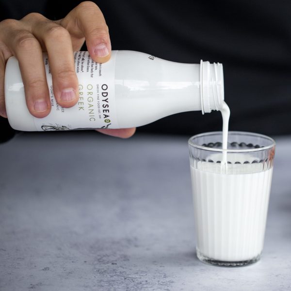 Hand pouring Odysea Goat's Kefir in a glass